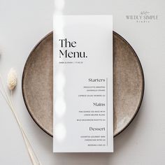 the menu is on top of a plate next to some dried flowers and a vase