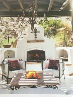 an outdoor living area with fireplace, chairs and table in front of the fire place