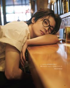 a woman leaning on a bar with her head resting on the counter next to a glass of beer