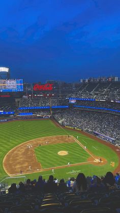 a baseball stadium filled with lots of people sitting in the bleachers at night