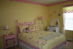 a child's bedroom with yellow walls and pink bedding, white dresser and mirror