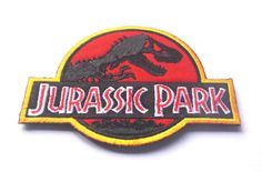 a red and black patch with the word jurassic park on it's side, in front of a white background