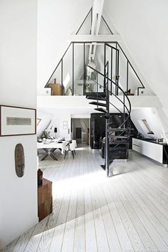 a room with white walls and wooden floors has a spiral stair case in the center