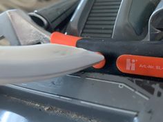 an orange and black knife sitting on top of a piece of metal