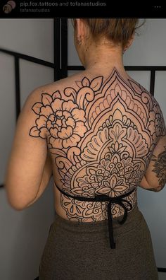 the back of a woman's body with tattoos on it