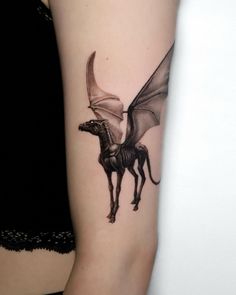 a woman's arm with a dragon and horse tattoo on the left side of her arm