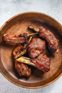 a wooden bowl filled with meat on top of a table