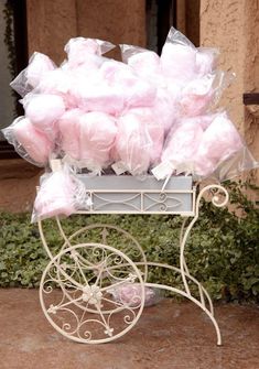 a white cart filled with lots of pink tissue wrapped in cellophane on top of a sidewalk