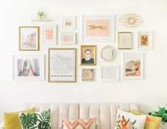 a living room filled with lots of framed pictures on the wall next to a couch