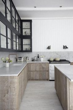 a kitchen with marble counter tops and wooden cabinets, along with black glass doors on the windows