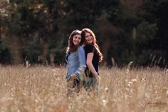 two women are hugging in the tall grass