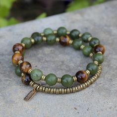 Jade and Tigers Eye Mala Bracelet. Made with genuine jade and tigers eye. Brass hand made beads support women in Africa. Contains 27 beads so its a wrist mala! Stringed on our signature and exclusive thick hitec elastic. Made in the USA. Jade is said to bring harmony to the wearer and to attract prosperity and abundance. Tiger's Eye is a stone of protection. It enhances integrity, willpower, practicality and correct use of power. Luxury Adjustable Agate Beaded Bracelets, Cheap Aventurine Beaded Bracelets, Luxury Agate Gemstone Beads Bracelets, Bead Board, Handmade Stuff, Coin Pendant Necklace, Beads Bracelet Design, Bead Ideas, Tiger Eye Bracelet