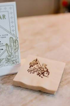 a small wooden coaster sitting on top of a table next to a paper napkin holder