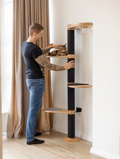 a man standing next to a tall cat tree