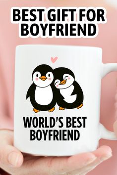 a person holding a white coffee mug with two penguins on it and the words best gift for boyfriend world's best boyfriend