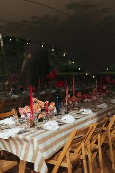 a long table is set with candles and plates for an outdoor dinner or function in the evening