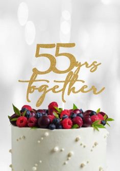 a white cake with gold lettering and berries on top that says 55 years together,