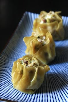 three dumplings on a blue and white plate with a black table cloth in the background