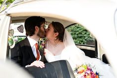 a bride and groom kissing in the back of a car