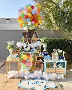 a birthday party with balloons and decorations on the ground, including a dog in front of a house