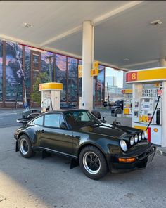 a black car is parked in front of a gas station with no one around it