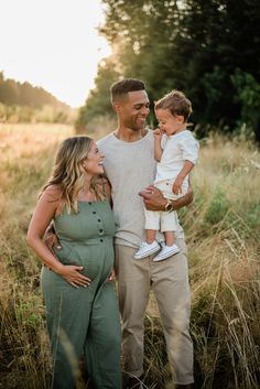 a man, woman and child standing in tall grass