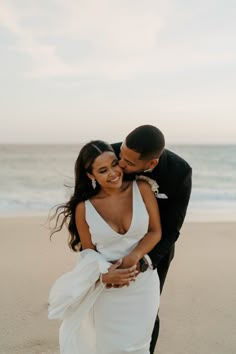 a newly married couple embracing on the beach