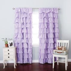 a white chair sitting next to a window covered in purple ruffled curtains and a potted plant