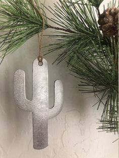 a metal cactus ornament hanging from a pine tree