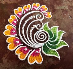 an artistic design made with colored powders on a brown table top in the shape of a flower