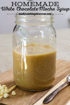 homemade white chocolate mocha syrup in a mason jar on a cutting board with spoons