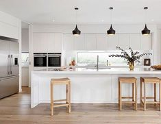 a kitchen with two stools and an island in the middle, surrounded by stainless steel appliances