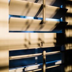 the shadow of a window and blinds in front of it is seen through an open window