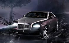 a rolls royce parked in the rain with its headlights on and water splashing around it