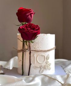 two red roses sitting on top of a white cake