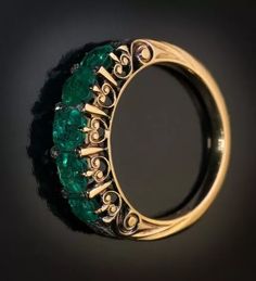 an emerald and diamond ring on a black background