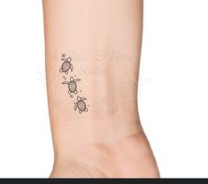 a small turtle tattoo on the left side of the arm, with two smaller turtles above it