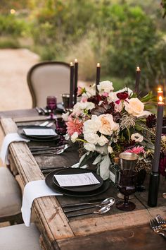 an outdoor table set with flowers and candles