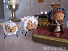 three little sheep standing next to each other on top of a table in front of an open book