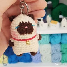 a hand holding a small crocheted keychain with a cat on it