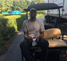 a man sitting on top of a chair in front of a golf cart holding a bag