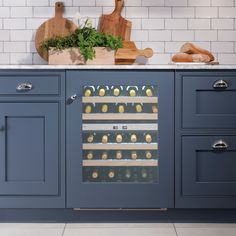 a wine cooler in the middle of a kitchen with blue cabinets and white tile walls