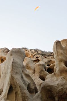 there is a kite that is flying in the sky above some rocks and sand formations