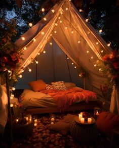 a bed covered in lights under a canopy with pillows and blankets on the floor next to it