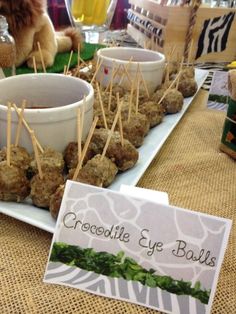 a table topped with bowls filled with meatballs and toothpicks next to a sign