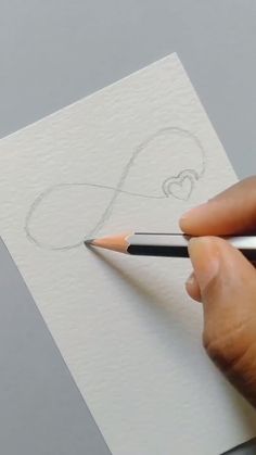 someone is drawing a heart with a pencil