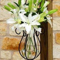 a vase filled with white flowers next to a brick wall