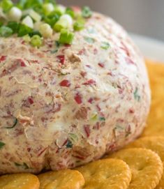 a cheese ball on top of crackers with green onions and celery sprinkles