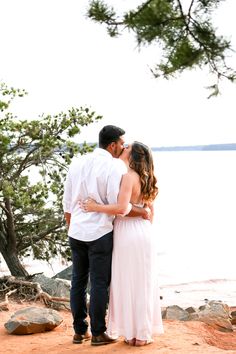 a man and woman standing next to each other near the water