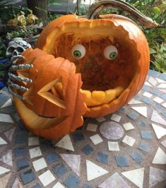 two carved pumpkins sitting on top of a mosaic table with eyes and hands in them